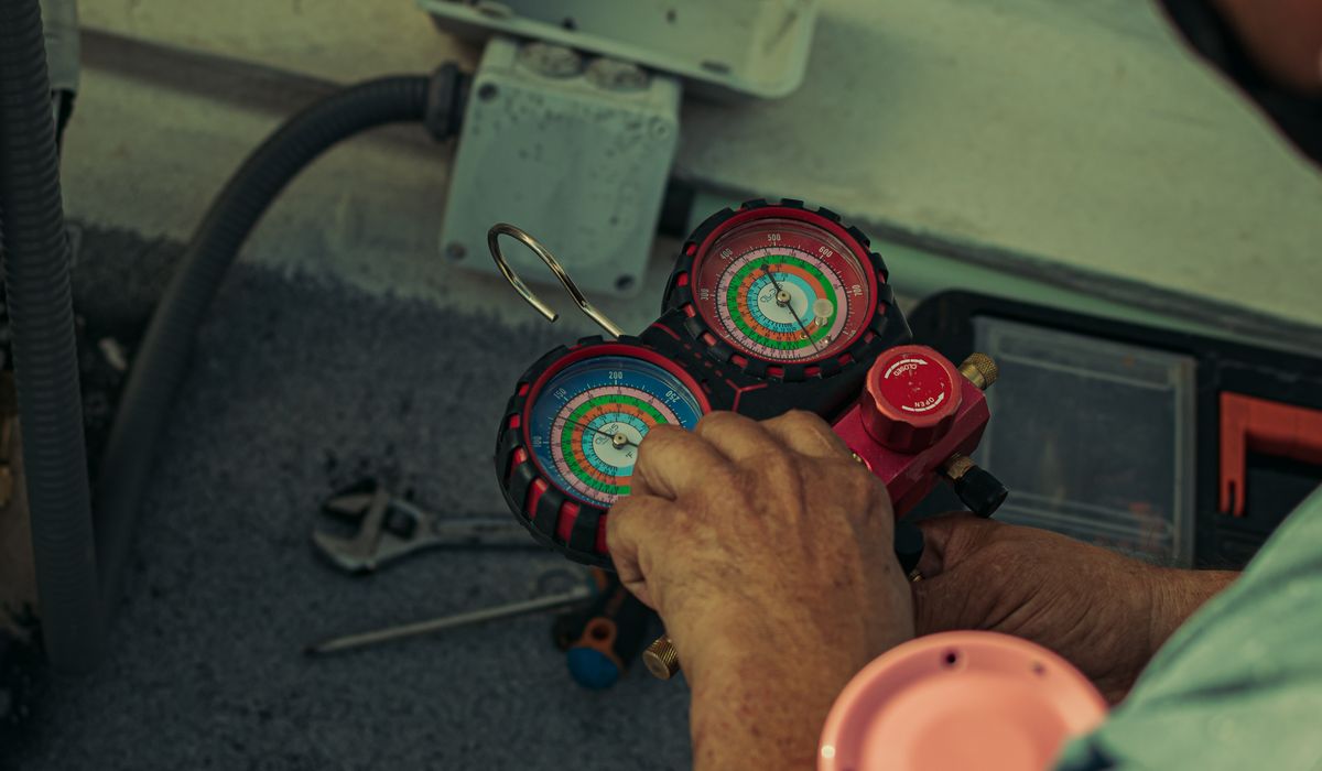 Close view of manifold gauges in a technician's hands during service